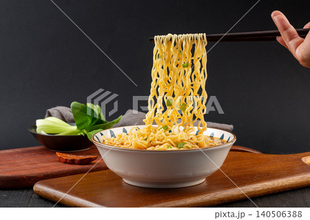 Bowl of Instant Noodles in Savory Broth Topped with Fresh Scallions. Quick Asian Ramen Soup, Comfort Food on Black Background. Bowl of Instant Noodles in Savory Broth Topped with Fresh Scallions. Quick Asian Ramen Soup, Comfort Food on Black Background. 140506388