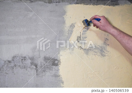 Person paints a wall yellow while waterproofing a bathroom under tiles. 140506539