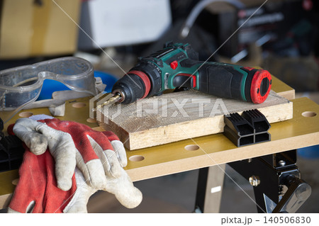 Cordless drill and safety gear ready for woodworking project on workbench 140506830
