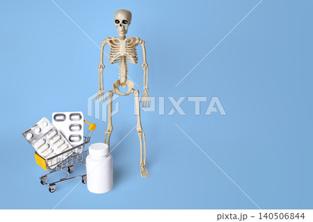 A Humorous Representation of a Skeleton Next to a Shopping Cart Filled with Medicine and Supplements 140506844