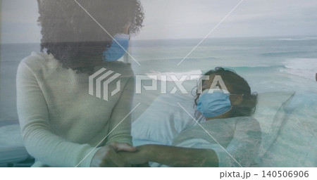 Holding adult hand, child leaning beside patient in hospital bed wearing gown, blue masks, sea view Holding adult hand, child leaning beside patient in hospital bed wearing gown, blue masks, sea view 140506906