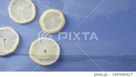 Displaying four lemon slices clustered on left of blue cloth with coastal horizon print, copy space 140506927