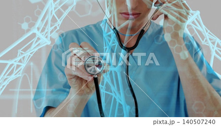 Showing doctor holding stethoscope in clinic, wearing blue scrubs with digital DNA helix overlays Showing doctor holding stethoscope in clinic, wearing blue scrubs with digital DNA helix overlays 140507240