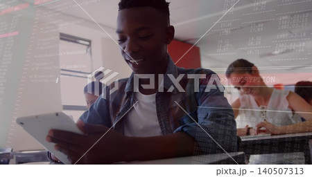 Smiling male student in denim shirt holding tablet at school, students writing, FileENCRYPTION 140507313
