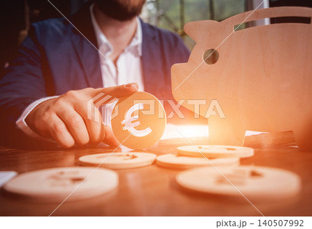 Businessman holds a coin near wooden piggy. Money box. Collecting money with earning bank. 140507992