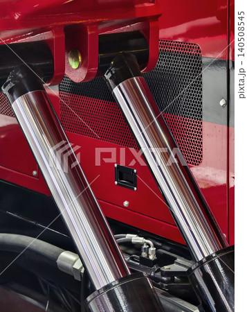 Close view of truck components showing hydraulic cylinders and engine details in a garage during daytime work 140508545