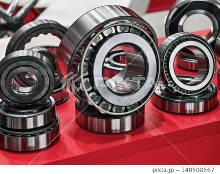Various types of ball bearings arranged on a red display table at a mechanical exhibition in an industrial setting 140508567
