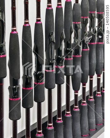 Fishing rods displayed on a rack at a store during the daytime showcasing various styles and designs for anglers Fishing rods displayed on a rack at a store during the daytime showcasing various styles and designs for anglers 140508595
