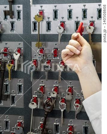 Choosing a key from a wall display of various keys and key holders in a storage area or office setting Choosing a key from a wall display of various keys and key holders in a storage area or office setting 140508608