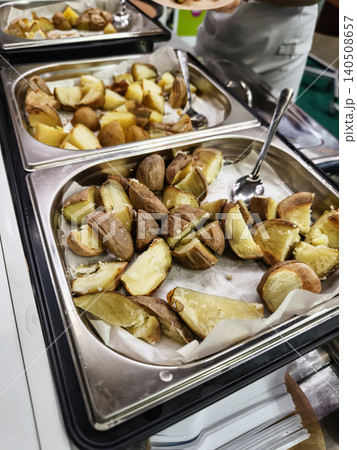Golden brown potatoes are served at a buffet in a dining hall during a community event Golden brown potatoes are served at a buffet in a dining hall during a community event 140508657
