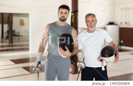 Two men of different ages after sparring at a fencing club Two men of different ages after sparring at a fencing club 140508969