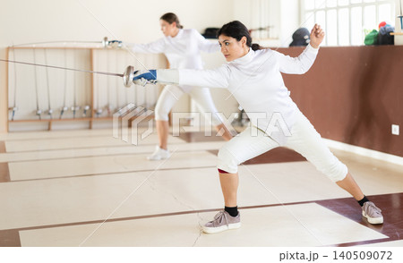 Latina woman in white overalls in fencing club 140509072