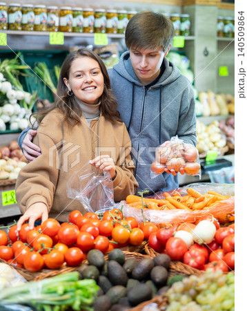 Young woman and young guy choose tomatoes Young woman and young guy choose tomatoes 140509864