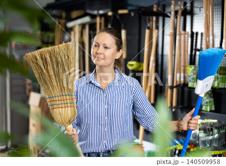 Casual woman holding two brooms while shopping in the supermarket Casual woman holding two brooms while shopping in the supermarket 140509958