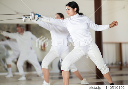 Men and women practicing epee moves in gym 140510102