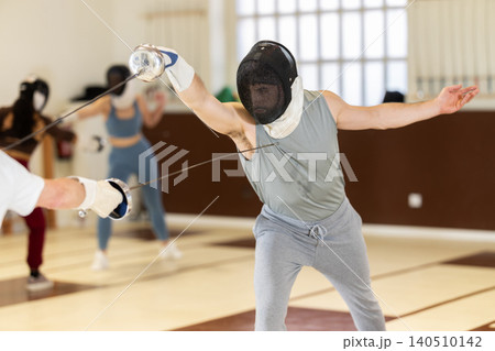 Men and women in helmets practicing sparring fights 140510142