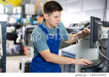 Man worker operating computerised machine to mix paint in paint shop 140510305