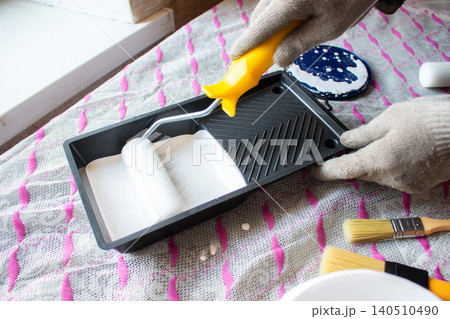 Hand dipping roller into paint tray. Spring home refresh. Budget friendly transformation. Small improvements, big mood boost. Smart spending Hand dipping roller into paint tray. Spring home refresh. Budget friendly transformation. Small improvements, big mood boost. Smart spending 140510490