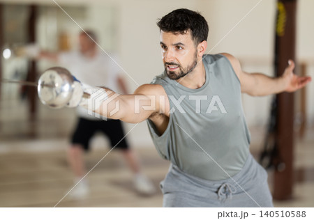 Adult male fencer practicing sword techniques Adult male fencer practicing sword techniques 140510588