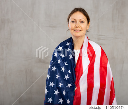 Happy young woman with flag of the USA against unicoloured background Happy young woman with flag of the USA against unicoloured background 140510674