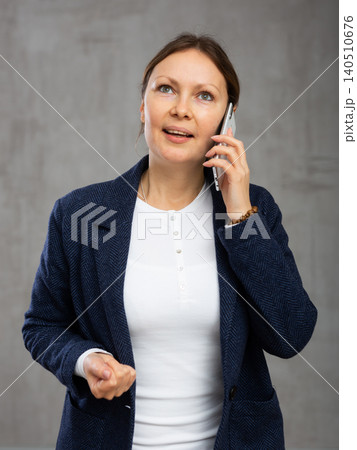 Smiling adult woman in jacket talking on phone Smiling adult woman in jacket talking on phone 140510676