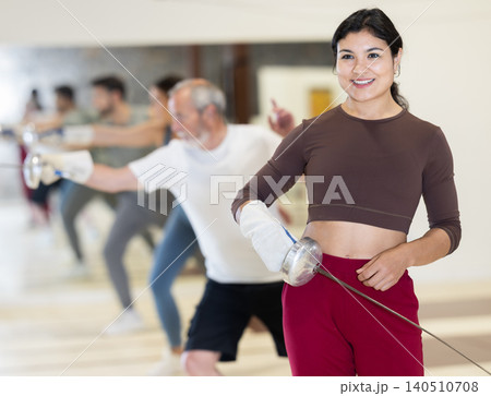 Portrait of a sporty woman holding foil during fencing training in gym 140510708