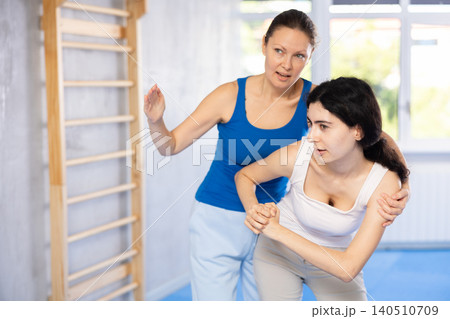 Woman is practicing self defence moves in pair with her female trainer at gym Woman is practicing self defence moves in pair with her female trainer at gym 140510709