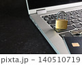 ノートパソコンのキーボードの上に置かれた南京錠とクレジットカード 140510719
