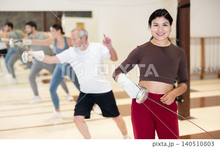 Portrait of a sporty woman holding foil during fencing training in gym Portrait of a sporty woman holding foil during fencing training in gym 140510803