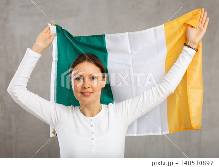 Adult cheerful woman holding Ireland flag Adult cheerful woman holding Ireland flag 140510897