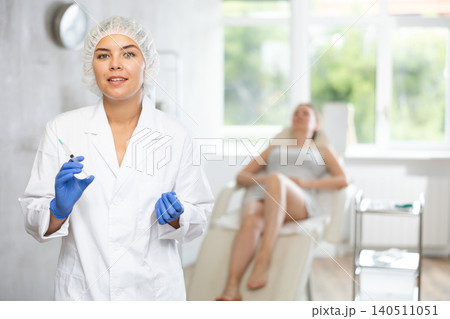 Nurse in disposable cap with syringe in hand and conducts preparatory activities before injections. 140511051
