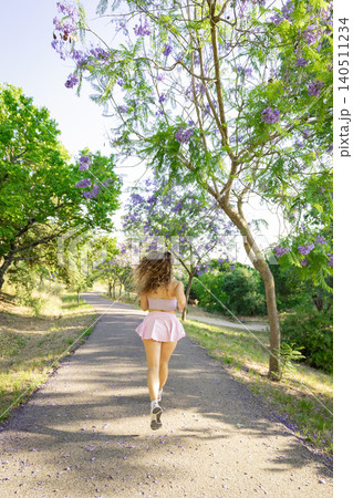 Running down a path surrounded by trees and flowers on a sunny day in a park Running down a path surrounded by trees and flowers on a sunny day in a park 140511234