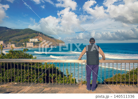 A man standing on the embankment and looking at the ocean and the beautiful bay. Bakio, Biscay, Basque Country, Spain, Europe A man standing on the embankment and looking at the ocean and the beautiful bay. Bakio, Biscay, Basque Country, Spain, Europe 140511336