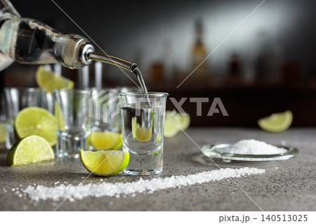Pouring Tequila into shot glass. Pouring Tequila into shot glass. 140513025