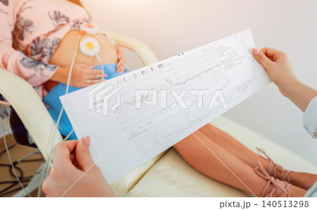 Pregnant woman with electrocardiograph check up for her baby. Fetal heart monitoring Pregnant woman with electrocardiograph check up for her baby. Fetal heart monitoring 140513298