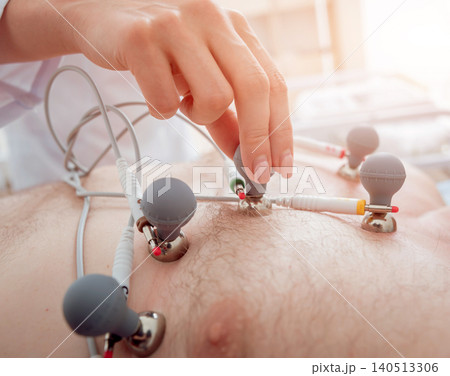 Doctor with electrocardiogram equipment making cardiogram test to patient in clinic. Doctor with electrocardiogram equipment making cardiogram test to patient in clinic. 140513306