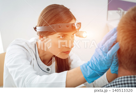 Otolaryngologist examine ear of young man. 140513320