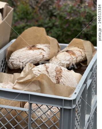 Artisan bread in a crate wrapped in brown paper, suitable for bakery background 140513384