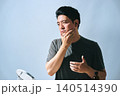 顔に手をあてる30代の日本人の男性の会社員が鏡を見てスキンケアをする男性 140514390