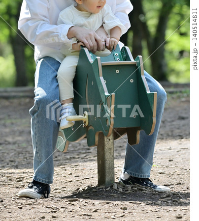 公園でスプリング遊具を楽しむ娘と父親 140514811