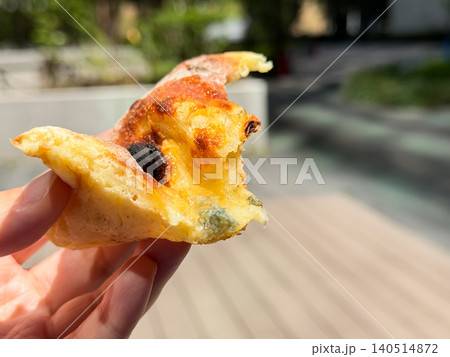 人の手で持った食べかけのパン。ゴルゴンゾーラチーズと蜂蜜をトッピングして焼いたピザ風のパン。 人の手で持った食べかけのパン。ゴルゴンゾーラチーズと蜂蜜をトッピングして焼いたピザ風のパン。 140514872