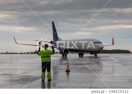 Airplane marshalling at the aiport in rainy weather. Passenger airliner meeting Airplane marshalling at the aiport in rainy weather. Passenger airliner meeting 140515312