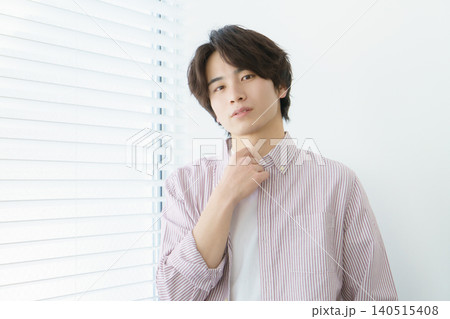 窓際に立つ縦縞のシャツを着る若い日本人男性のポートレート 140515408