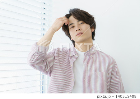 窓際に立つ縦縞のシャツを着る若い日本人男性のポートレート 140515409