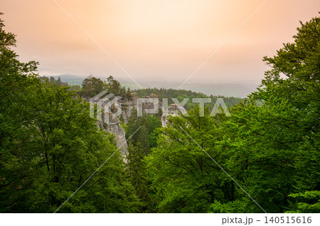 Rock city formations in Hruba Skala, Bohemian Paradise (Cesky raj), rising from forest seen from above. Orange sunrise sky lights sandstone towers and valleys panoramic view sky . Rock city formations in Hruba Skala, Bohemian Paradise (Cesky raj), rising from forest seen from above. Orange sunrise sky lights sandstone towers and valleys panoramic view sky . 140515616