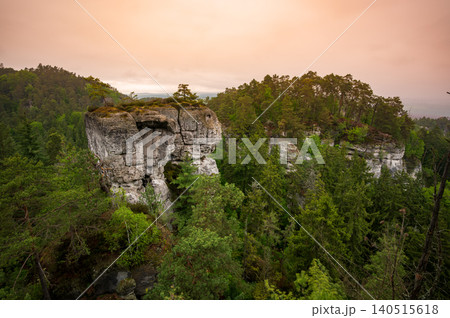 Rock city formations in Hruba Skala, Bohemian Paradise (Cesky raj), rising from forest seen from above. Orange sunrise sky lights sandstone towers and valleys panoramic view sky . Rock city formations in Hruba Skala, Bohemian Paradise (Cesky raj), rising from forest seen from above. Orange sunrise sky lights sandstone towers and valleys panoramic view sky . 140515618