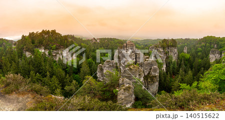 Rock city formations in Hruba Skala, Bohemian Paradise (Cesky raj), rising from forest seen from above. Orange sunrise sky lights sandstone towers and valleys panoramic view sky . Rock city formations in Hruba Skala, Bohemian Paradise (Cesky raj), rising from forest seen from above. Orange sunrise sky lights sandstone towers and valleys panoramic view sky . 140515622