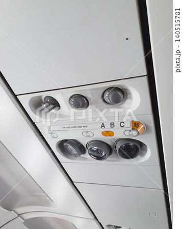 Airplane ceiling panel with air conditioning vents and reading lights above seat row. Aviation interior equipment for passenger comfort and cabin safety control in commercial aircraft. Airplane ceiling panel with air conditioning vents and reading lights above seat row. Aviation interior equipment for passenger comfort and cabin safety control in commercial aircraft. 140515781