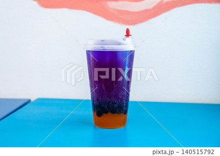 Blue galaxy bubble tea with butterfly pea tea and boba pearls in a plastic cup. Layered refreshing beverage served in a cafe. Modern drink concept, trendy cold fruit milk tea snack. Blue galaxy bubble tea with butterfly pea tea and boba pearls in a plastic cup. Layered refreshing beverage served in a cafe. Modern drink concept, trendy cold fruit milk tea snack. 140515792