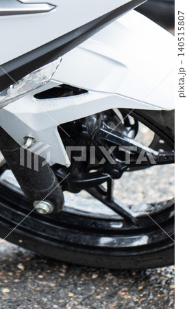 Motorcycle front wheel detail close-up, modern design of vehicle, white bodywork and black tire, mechanical engineering components, vertical orientation photograph, vertical photo Motorcycle front wheel detail close-up, modern design of vehicle, white bodywork and black tire, mechanical engineering components, vertical orientation photograph, vertical photo 140515807